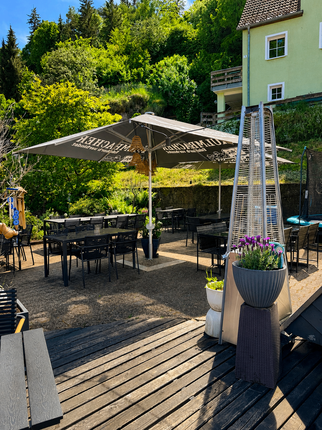 Biergarten des Restaurant Moena mit Sonnenschirm und Blick ins Grüne
